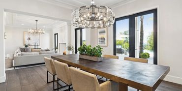 Modern dining room with beige chairs and a unique chandelier overlooking a patio.
