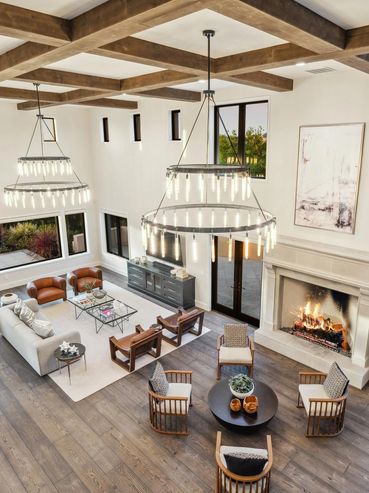 Spacious modern living room with high ceilings, large windows, and a cozy fireplace.