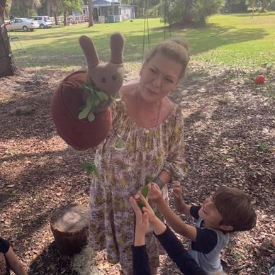 Woman with puppet entertaining children outdoors.
