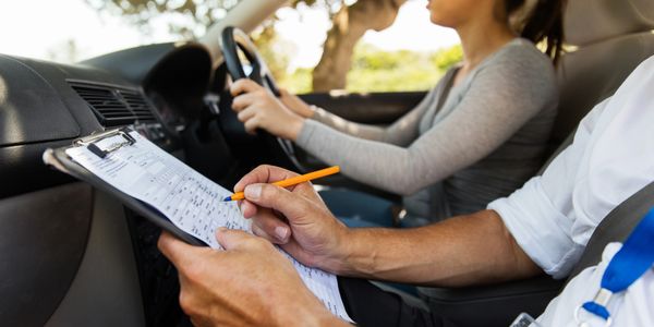 A driver instructor taking some notes while a student is driving