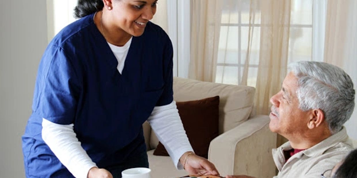 A nursing aid assisting a patient with their meal.