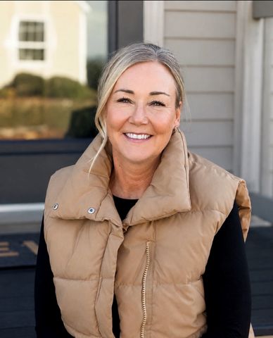 Smiling woman wearing a tan puffer vest.