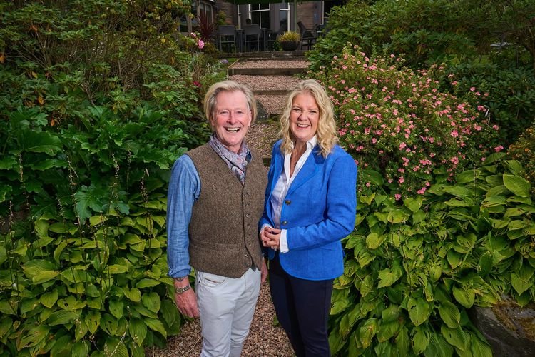 Paul Mudd and Jane Mudd, founders of the Mudd Partnership standing outdoors smiling.