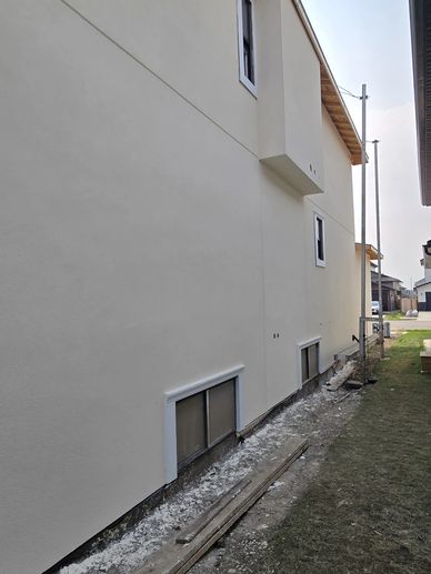 Side view of a beige house with windows and a grassy yard.