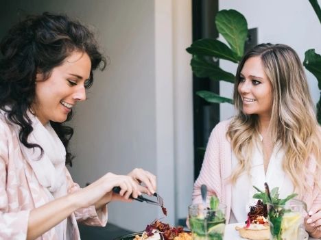Two female friends eating a healthy lunch with numerous anti-viral ingredients, at an outdoor table