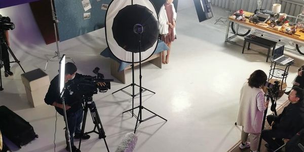 Photography studio setup with models, cameras, and lighting equipment.