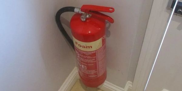 Red foam fire extinguisher mounted in a corner near a door.