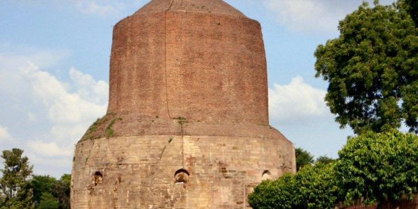 Ancient brick and stone stupa under blue sky.