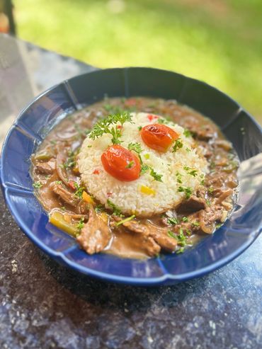 Plate of rice with stew, garnished with roasted tomatoes and herbs.