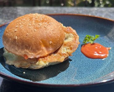Egg sandwich on a sesame bun with a side of ketchup and garnish on a blue plate.