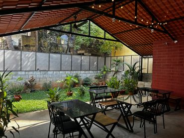 Cozy outdoor seating area with black chairs and tables under a red tiled roof.