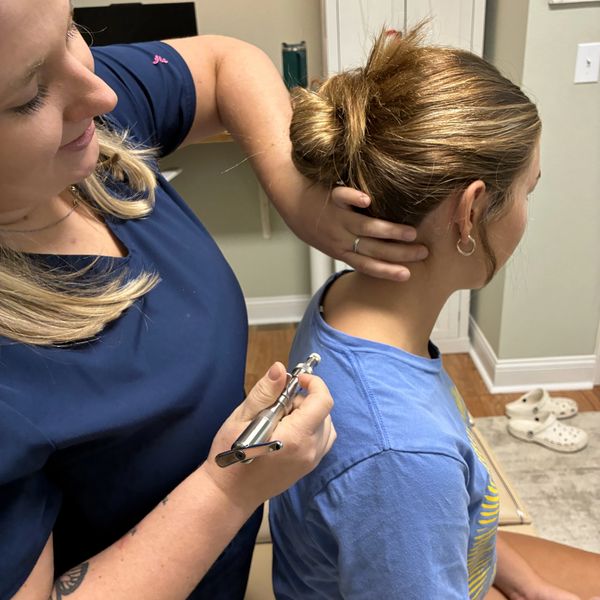 Chiropractor performing neck adjustment on patient.