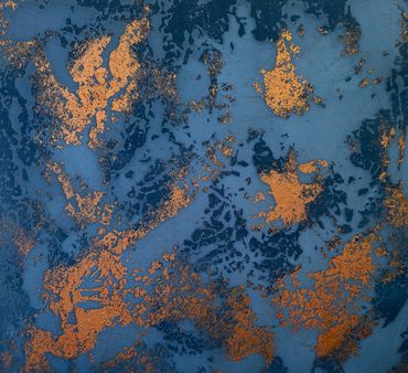 Abstract blue and gold textured surface with irregular patterns.
