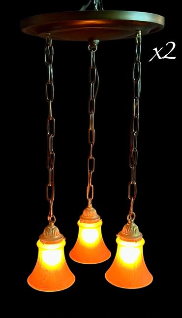 Three vintage pendant lights with warm orange glow hanging from chains.
