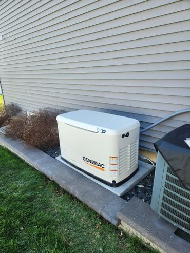 A Generac standby generator installed outside a house against the wall.