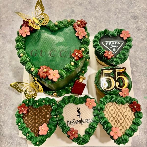 Heart-shaped luxury brand-themed cupcakes with green frosting and floral decorations.