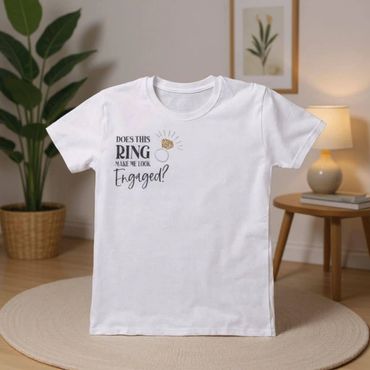 White t-shirt with engagement ring graphic and text asking if it makes the wearer look engaged.