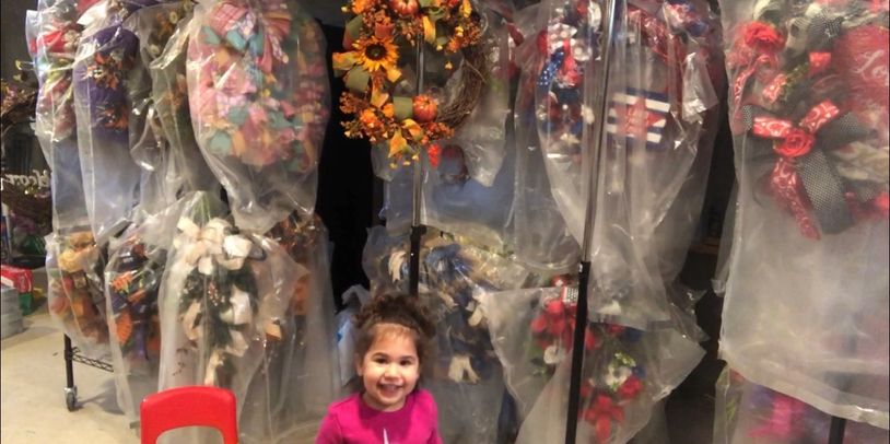 Toddler girl standing in front of wrath storage while looking at camera.