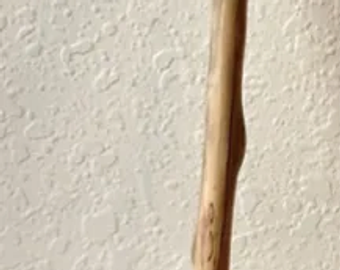 A wooden stick leaning against a textured wall.