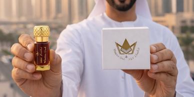 Man holding a perfume bottle and a branded box outdoors.