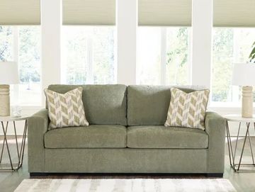 Green sofa with patterned pillows in a bright living room.
