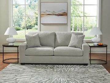 Modern living room setup with gray sofa and rugs.