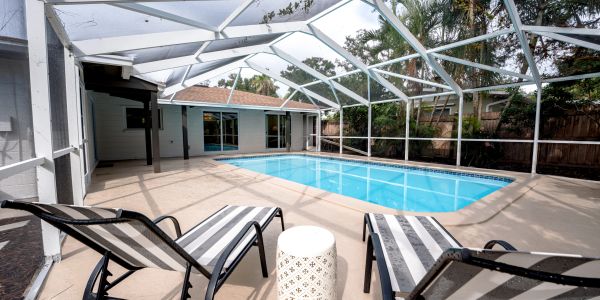 Screened pool area with lounge chairs and small table.