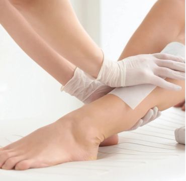 Applying a waxing strip on a person's leg for hair removal.