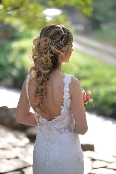 Bride with intricate curled hairstyle and lace wedding dress.