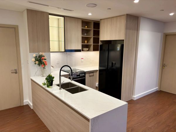 Modern kitchen with light wood cabinets and marble countertops.