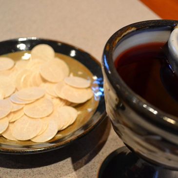 A plate of communion wafers next to a chalice filled with wine and juice.