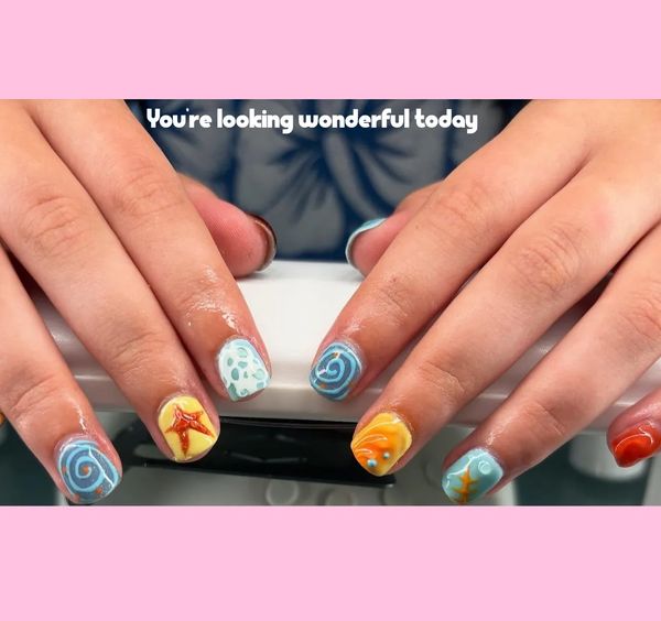 Colorful ocean-themed nail art on hands with positive message.