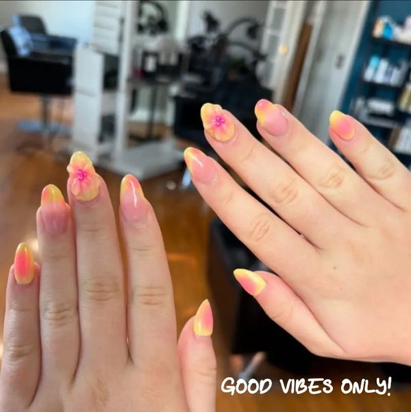 Bright yellow and pink ombre nails with 3D flower accents and 'Good Vibes Only!' text.