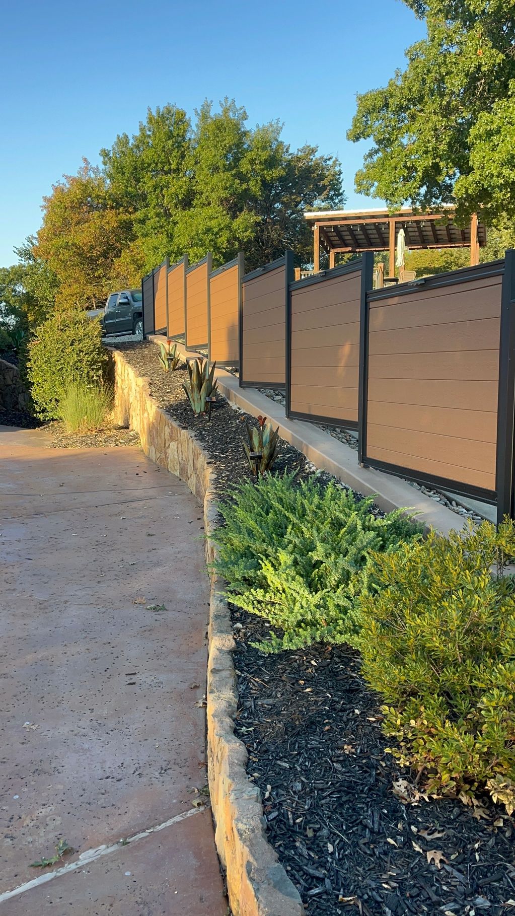 Modern privacy fence on a raised garden bed beside a driveway.