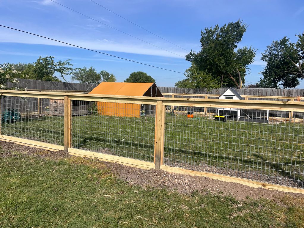 A fenced backyard with two small sheds and green grass.