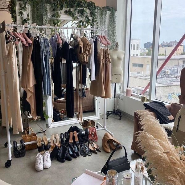 Stylish clothing rack with shoes and accessories in a bright, modern room with large windows.