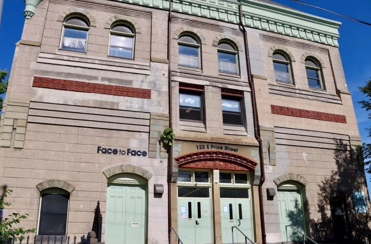 Historic building with multiple arched windows and green doors under a clear blue sky.