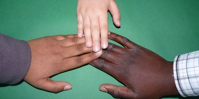 The hands of three adolescents of three different races reaching for each other