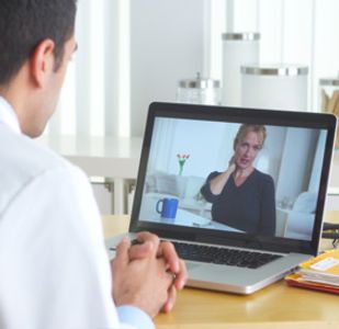 A physician listens to a patient who is speaking with them remotely via a web application