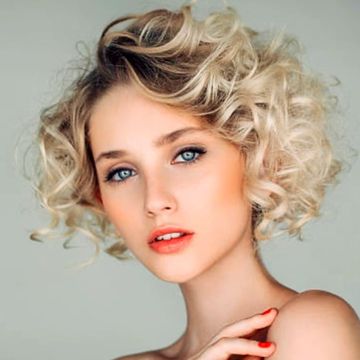 Portrait of a young woman with curly blonde hair and blue eyes.
