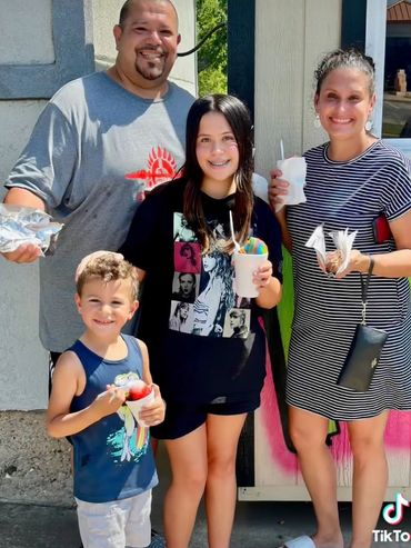 Happy family enjoying colorful treats outdoors on a sunny day.