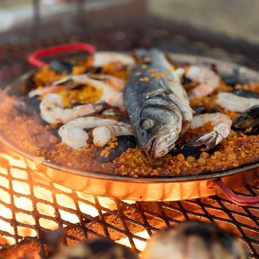 Seafood paella cooking over an open flame grill, a luxury add-on for La Cortadora events.