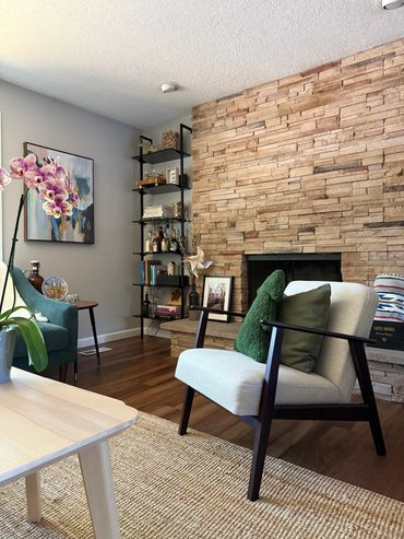 Cozy living room with modern armchair, stone fireplace, and decorative shelves.