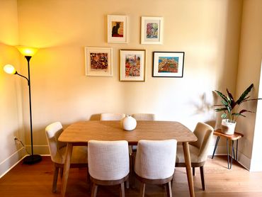 Cozy dining area with wooden table, beige chairs, and wall art.