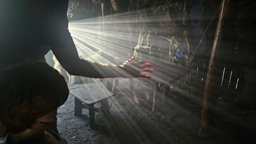 Sunlight streams through a rustic room, illuminating a hand and a child's silhouette.
