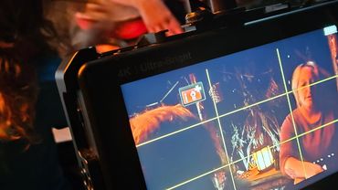 Camera monitor showing a person being filmed indoors with warm lighting.