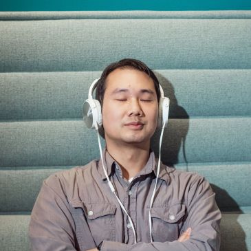 Person wearing headphones listening to a mental health podcast.