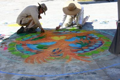 two women color in a large phoenix sidewalk art piece