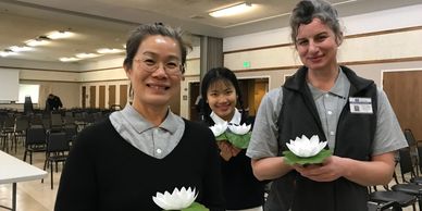 Bobbie Rae Jones and two Asian women hold paper lotus flowers