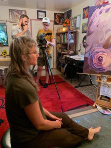Bobbie Rae Jones is being filmed in her studio amongst her art by two white men